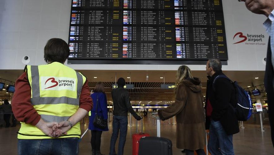 Des passagers regardent le panneau des départs à l'aéroport de Bruxelles le 8 décembre 2014