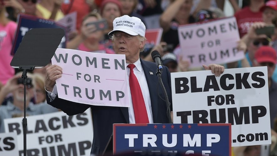 Donald Trump brandit deux panneaux "Les femmes avec Trump" et "Les noirs avec Trump", le 12 octobre 2016 à Lakeland en Floride
