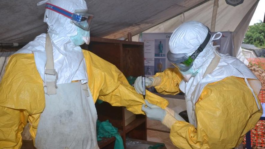 Des agents de santé mettent des vêtements de protection contre le virus Ebola, le 8 décembre 2014 dans un centre médical à Conakry