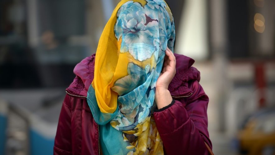 Une femme se protège le visage avec un foulard, à Pékin le 7 décembre 2015