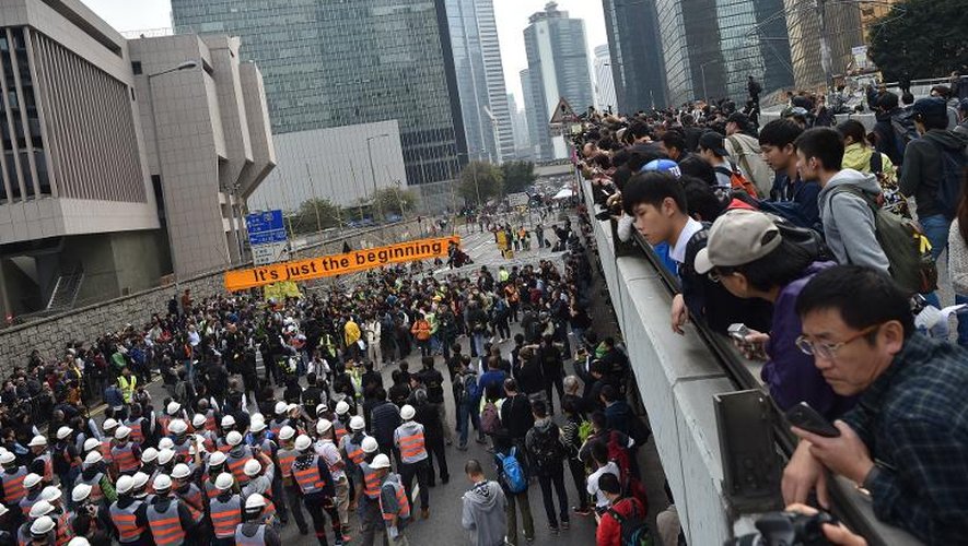 Des passants regardent les autorités qui se préparent à démanteler les barricades érigées par les prodémocrates, à Hong Kong, le 11 décembre 2014