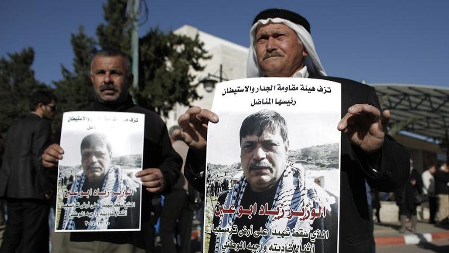 Des hommes tiennent des portraits de Ziad Abou Eïn dans une rue de Ramallah, le 10 décembre 2014 pour protester contre sa mort