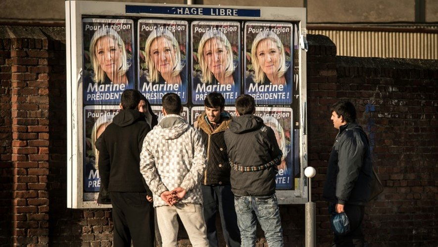 Des migrants regardent les panneaux électoraux à Calais avec en affiche la tête de liste FN de la région Nord, Marine Le Pen, le 7 décembre 2015