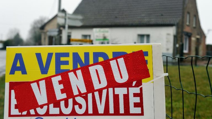 Un panneau d'agence immobilière devant une maison, dans le nord de la France
