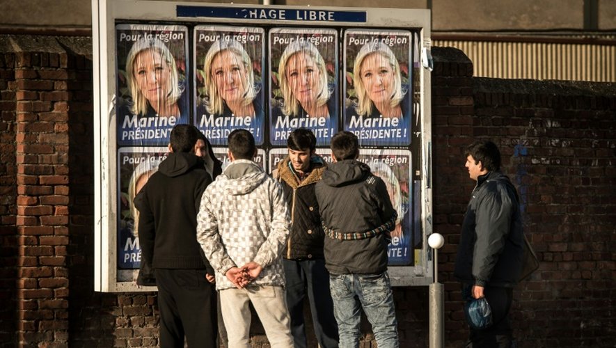 Des migrants regardent les panneaux électoraux à Calais avec en affiche la tête de liste FN de la région Nord, Marine Le Pen, le 7 décembre 2015