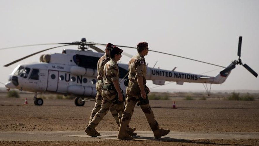Des soldats français passent devant un hélicoptère de l'ONU stationné sur la base militaire française à Gao, le 31 décembre 2013