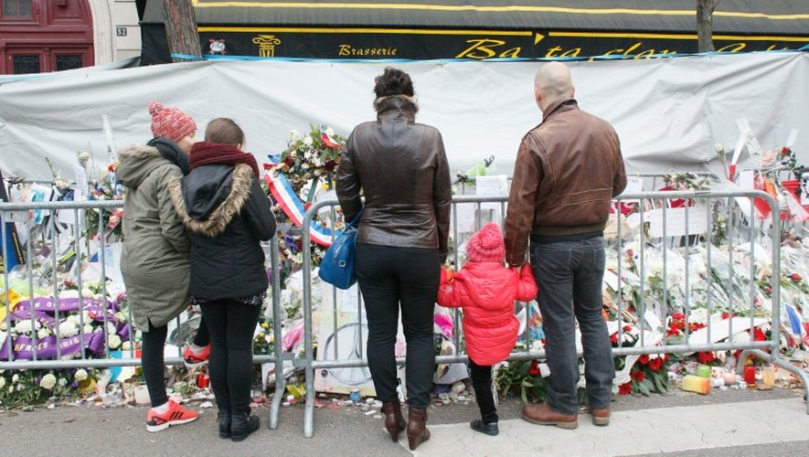 Des passants se recueillent devant la salle du Bataclan le 13 décembre 2015, où ont été déposés des bouquets en hommage aux victimes de l'attentat