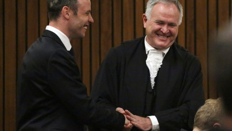 L'ancien champion paralympique sud-africain Oscar Pistorius (g) se félicite le 8 décembre 2015 à Pretoria de sa libération sous caution avec son avocat, Barry Roux