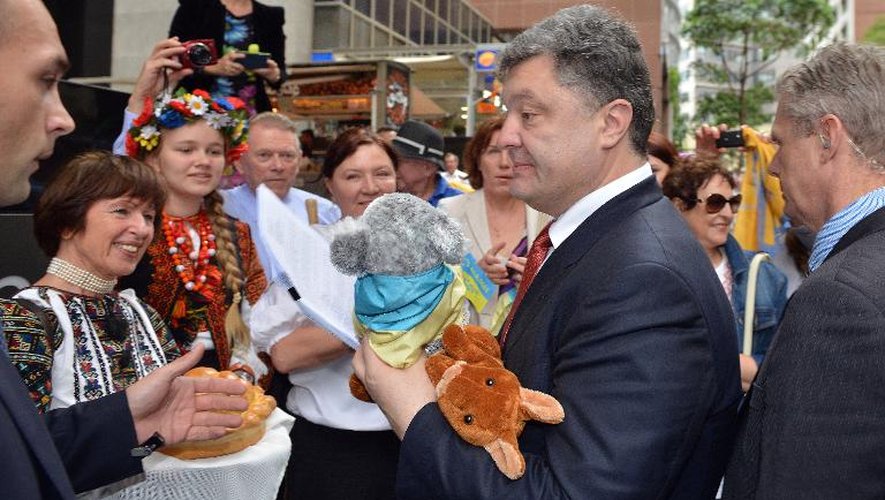 Le président ukrainien Petro Porochenko (2e d) tient un kangourou et un koala en peluche offerts par les membres de la communauté ukrainienne en Australie, lors de sa visite le 12 décembre 2014 à Sydney