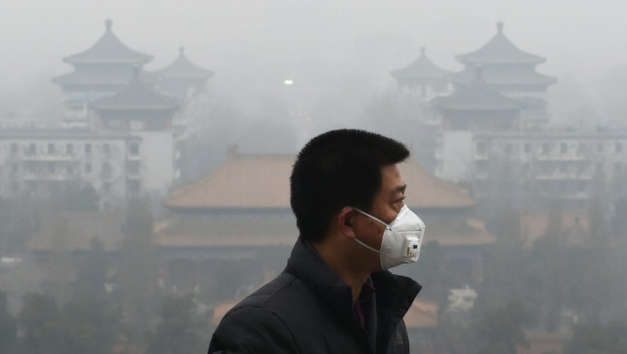 Un homme porte un masque pour se protéger de l'épais brouillard toxique qui submerge Pékin, le 8 décembre 2015