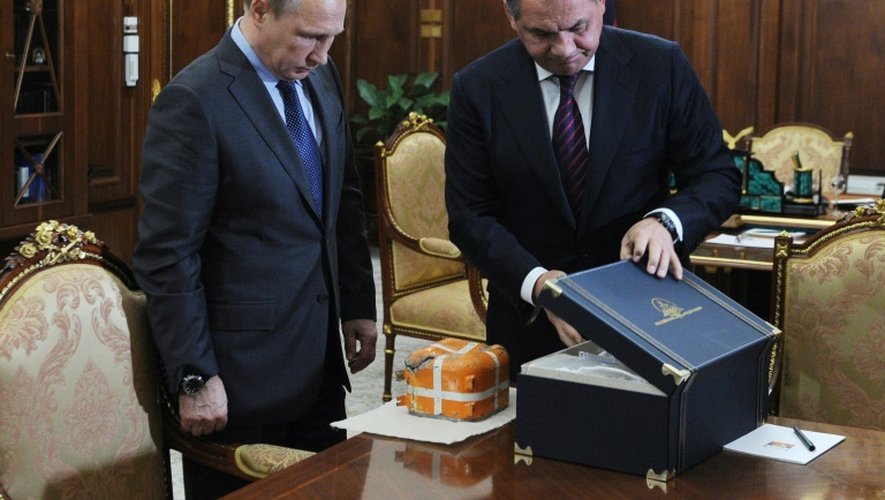 Le président Vladimir Poutine (g) et son ministre de la Défense Sergei Shoigu (d) examinent la boîte noire du bombardier russe ciblé par l'armée turque, le 8 décembre 2015 à Novo-Ogaryavo près de Moscou