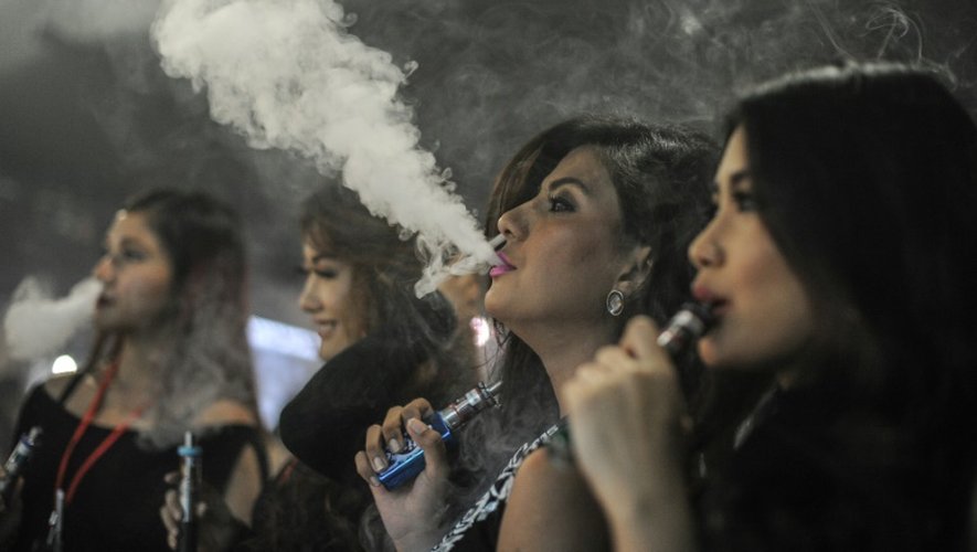 Des personnes fument des cigarettes électroniques pendant la VapeFair à Kuala Lumpur, le 5 décembre 2015