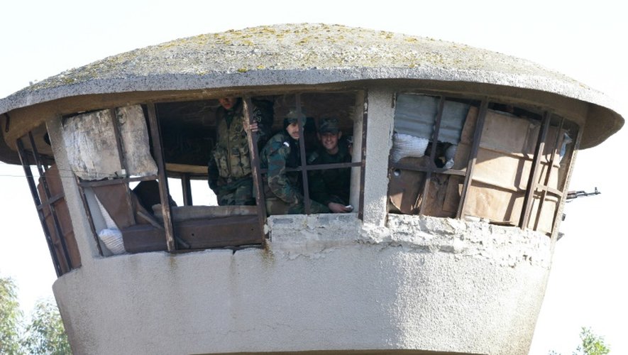 Des membres des forces syriennes surveillent l'évacuation d'un quartier de Homs le 9 décembre 2015