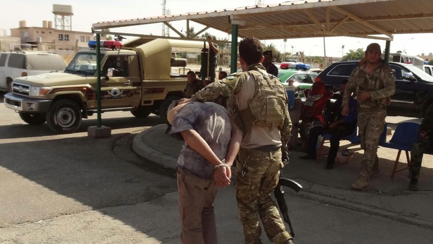 Un membre des forces de sécurité irakiennes escorte un membre présumé du groupe Etat Islamique arrêté la veille de l'attaque lancée à Kirkouk, le 22 octobre 2016