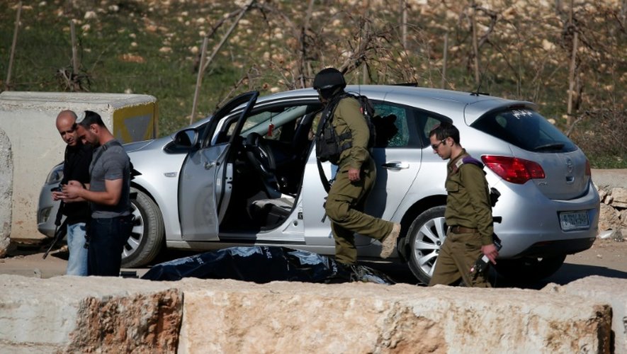 Des soldats israéliens contrôlent le 11 décembre 2015 la voiture d'un Palestinien, abattu dans une tentative d'attaque anti-israélienne à la voiture-bélier au check-point de Halhul, au nord de Hébron, en Cisjordanie
