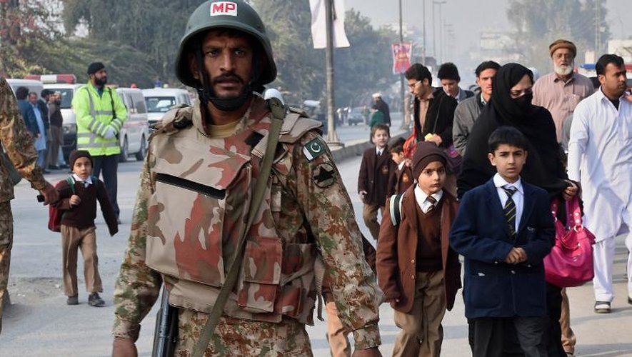 Un soldat pakistanais se tient devant des parents venant chercher leurs enfants dans une école de Peshawar où a eu lieu une attaque des Talibans le 16 décembre 2014