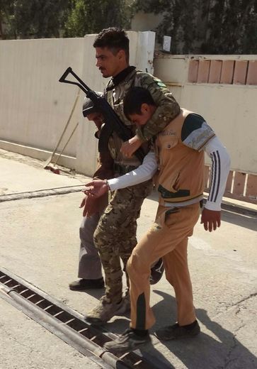 Un membre des forces de sécurité kurdes escorte un homme suspecté d'être un jihadiste de  l'EI, lors d'une patrouille à Kirkouk, le 22 octobre 2016