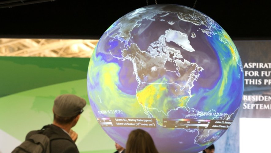 Des visiteurs regardent le globe terrestre à la conférence sur le climat au Bourget