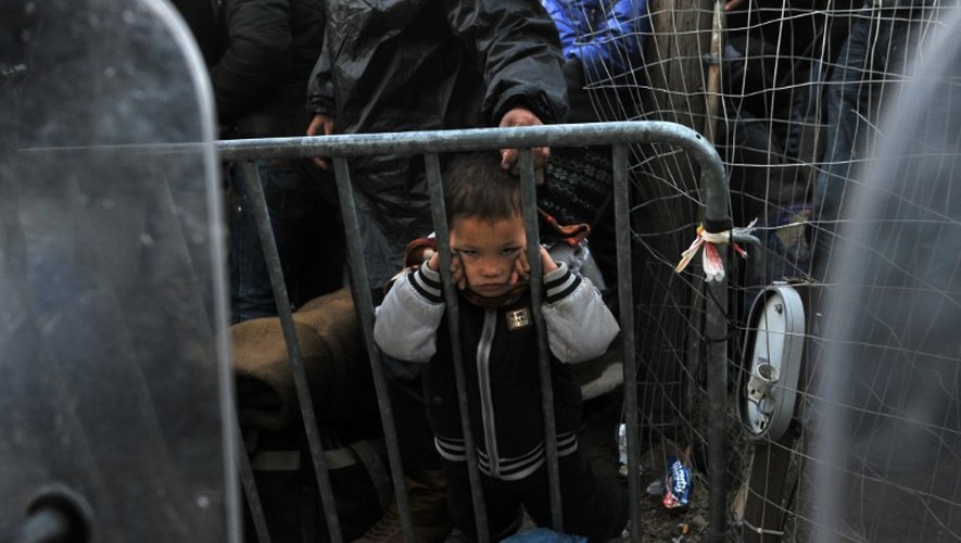 Un enfant attend avec d'autres réfugiés de traverser la frontière entre la Grèce et la Macédoine à Idomeni, le 3 décembre 2015