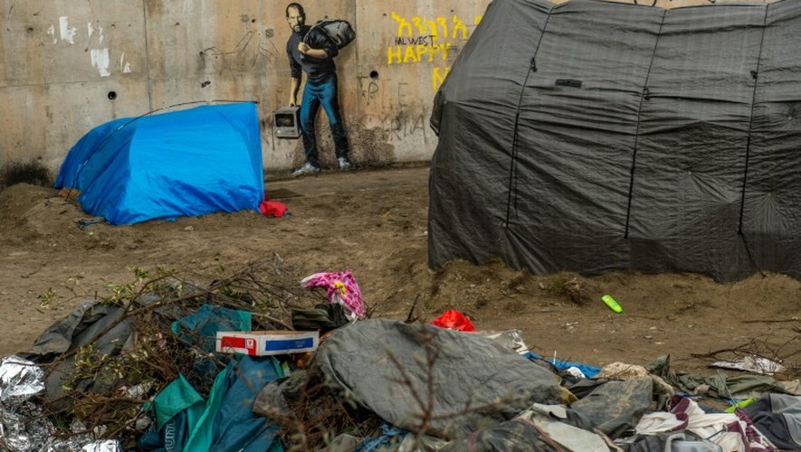 Des tentes de migrants devant une oeuvre de l'artiste britannique Banksy photographiée le 12 décembre 2015 et située à l'entrée de la "Jungle" de Calais