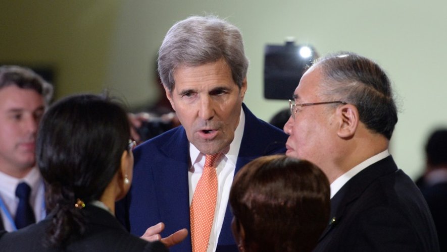 Le secrétaire d'Etat américain John Kerry (c) discute avec des délégués de différents pays lors de la COP21 à Paris le 12 décembre 2015
