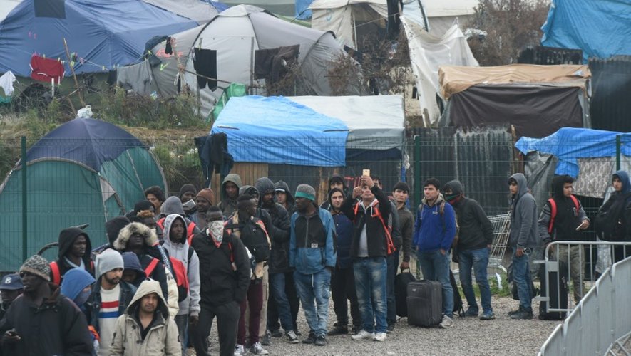 Des migrants en file d'attente lors de l'évacuation de la "Jungle" le 24 octobre 2016 à Calais