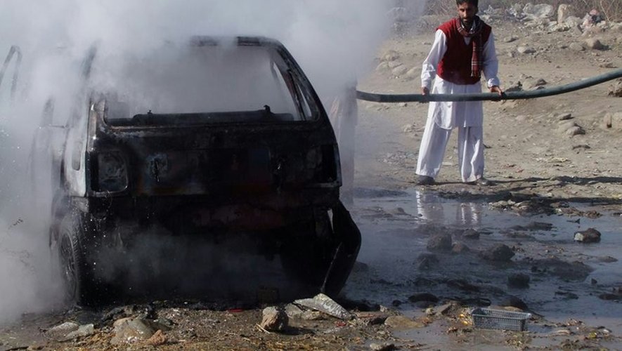 Un pompier pakistanais tente d'éteindre une voiture en feu à cause de l'explosion d'une bombe sur un marché de Parachinar, le 13 décembre 2015