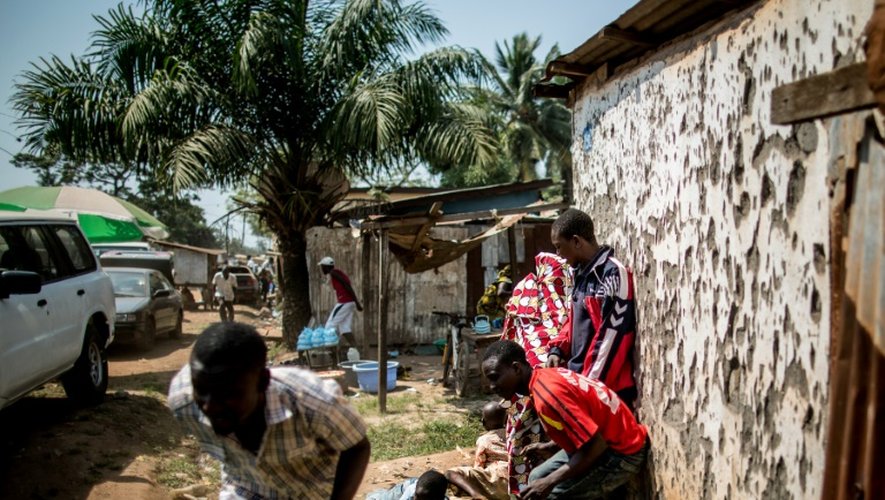 Des hommes se mettent à l'abri pendant que des tirs à l'arme lourde retentissent à Bangui, le 13 décembre 2015