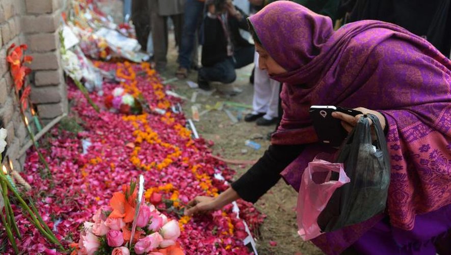 Un parterre de fleurs est installé le 18 décembre 2014 à l'extérieur de l'école où 148 personnes, dont 132 enfants et adolescents, ont trouvé la mort à la suite d'une attaque menée par un commando du Mouvement des talibans du Pakistan (TTP) à Peshawar