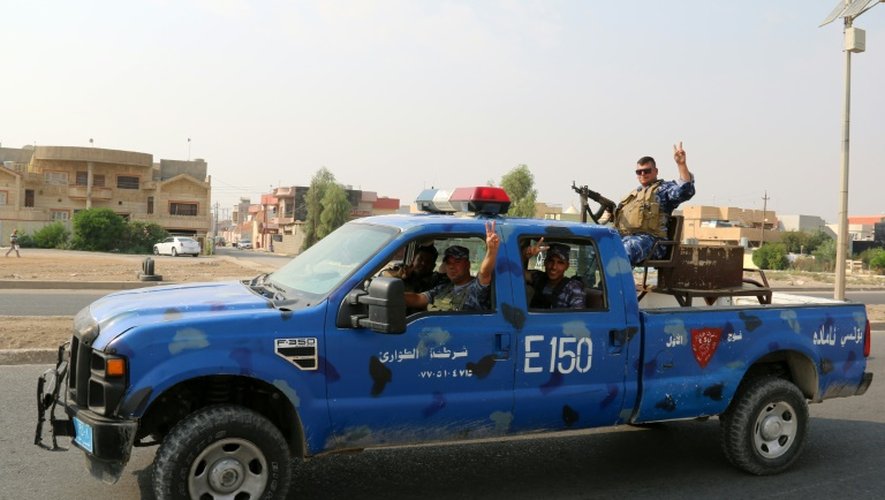 Des policiers irakiens font le signe de la victoire en patrouillant dans les environs de Kirkouk, le 25 octobre 2016
