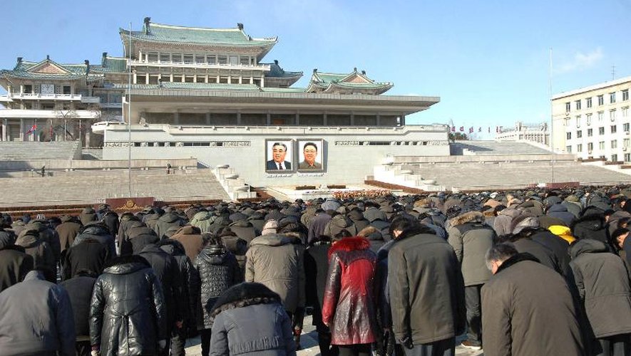 Des personnes s'inclinent le 17 décembre 2014 à Pyongyang devant les portraits des défunts dirigeants  Kim Il-Sung et Kim Jong-Il à l'occasion du troisième anniversaire de la mort de Kim Jong-Il