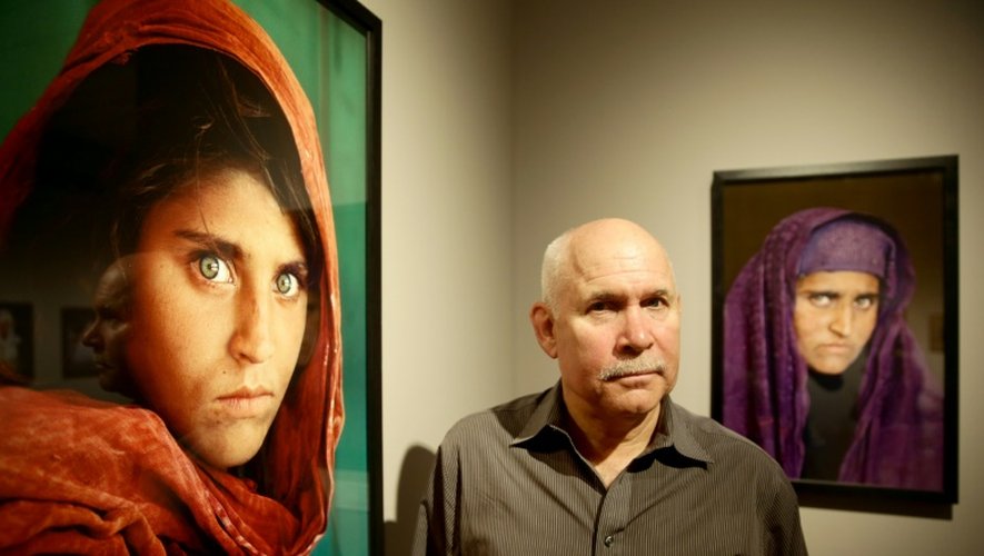 Le photographie américain Steve McCurry pose à côté de sa photo de la "fille afghane" aux yeux verts Sharbat Gula, lors d'une exposition en 2013 à Hamburg, dans le nord de l'Allemagne