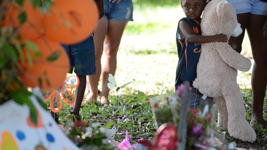Un petit garçon apporte, le 20 décembre 2014, un ours en peluche devant le mémorial improvisé dasn un parc situé près de la propriété où huit enfants et adolescents ont été tués à Cairns, dans le nord de l'Australie