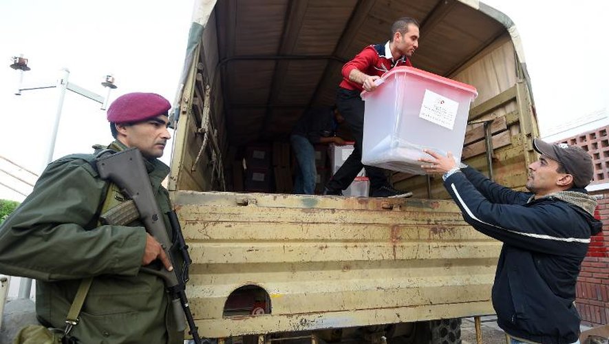Des employés de l'instance électorale déchargent des urnes d'un véhicule militaire sous la surveillance de l'armée, avant que celles-ci ne soient installées dans les bureaux de vote du gouvernorat de Ben Arous, en Tunisie, le 20 décembre 2014