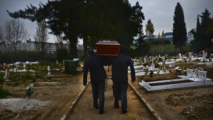 Des employés des pompes funèbres portent le cercueil d'un mort anonyme dans le cimetière de Lisbonne le 12 décembre 2014