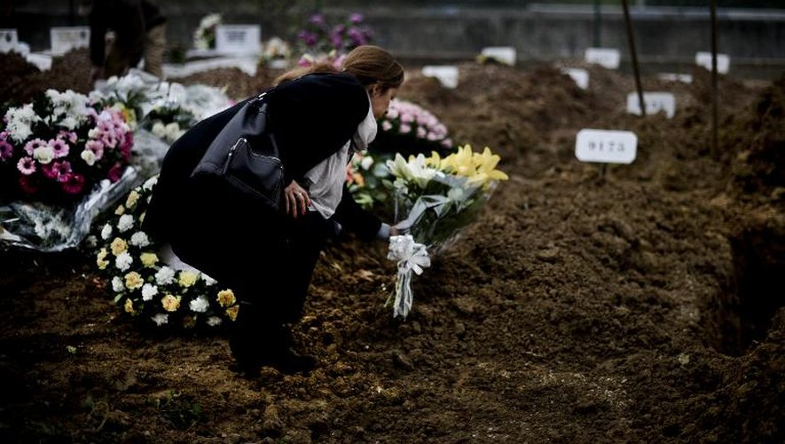 Un membre de la confrérie catholique de la Miséricorde et de Saint Roch dépose des fleurs lors de l'enterrement d'un mort anonyme le 12 décembre 2014 au cimetière de Lisbonne