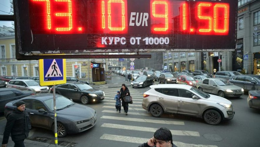 Un homme au téléphone passe sous un panneau indiquant le taux de change du rouble le 17 décembre 2014 à Moscou