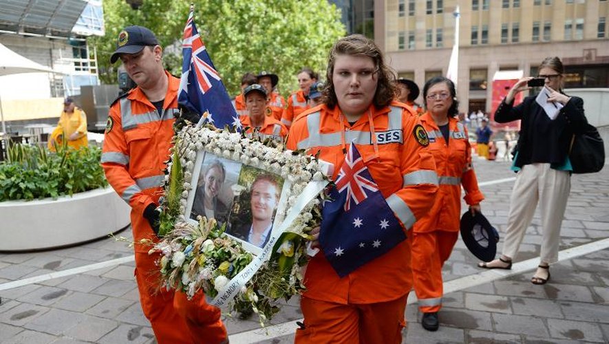 Des volontaires défilent avec les photos de Katrina Dawson et Tori Johnson à Sydney le 23 décembre 2014, les deux otages tués lors de l'assaut du Lindt Café le 16 décembre