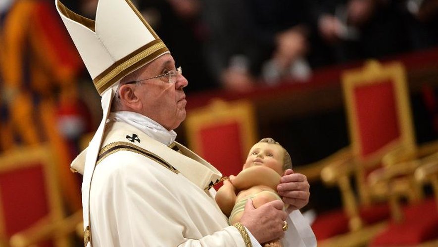 Le Pape François porte l'enfant Jésus lors de la messe de Noël à la Basilique Saint Pierre au Vatican le 24 décembre 2014