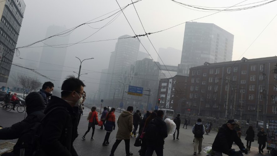 Des gens traversent une rue à Pékin un jour de pollution le 14 décembre 2015