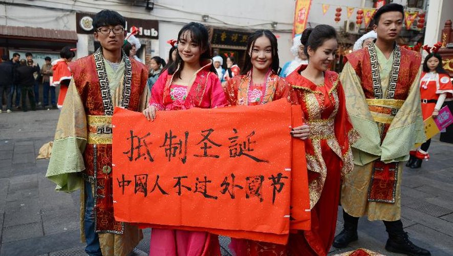 Des étudiants habillés en tenue traditionnelle chinoise le 24 décembre 2014 à Changsha tiennent une bannière sur laquelle est écrit "Résistons à Noël, les Chinois ne devraient pas célébrer des fêtes étrangères"