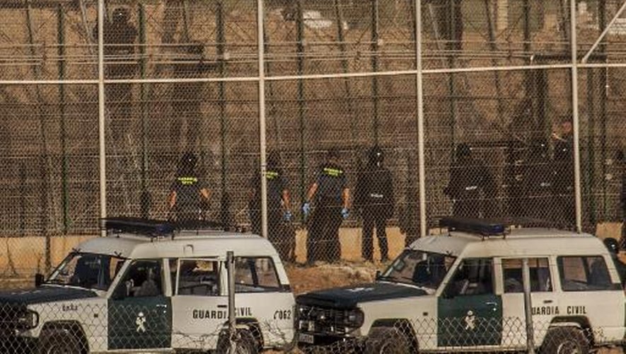 Des policiers espagnols empêchent des migrants d'escalader les grillages qui servent de frontières entre Mellila, enclave espagnole, et le Maroc, le 14 août 2014