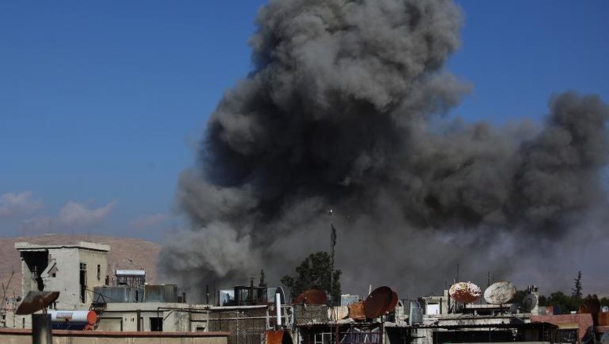 De la fumée s'échappe des immeubles lors de bombardements sur la ville assiégée de Douma (Syrie) le 23 décembre 2014
