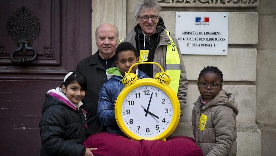 Jean-Baptiste Eyraud (C), porte-parole du DAL, pose avec Mgr Jacques Gaillot et des enfants devant le ministère du Logement avec un réveil, pour lui demander de "se réveiller", le 25 décembre 2014 à Paris