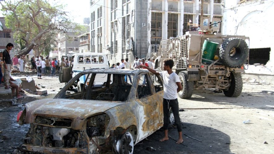 Un jeune regarde une voiture brûlée à proximité de l'endroit où a eu lieu une  attaque suicide à la voiture piégée contre la Banque centrale du Yémen à Aden le 29 octobre 2016