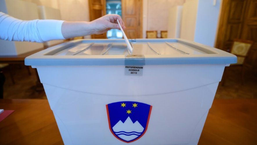 Un électeur dépose son bulletin dans l'urne le 20 décembre 2015 à Bled en Slovénie