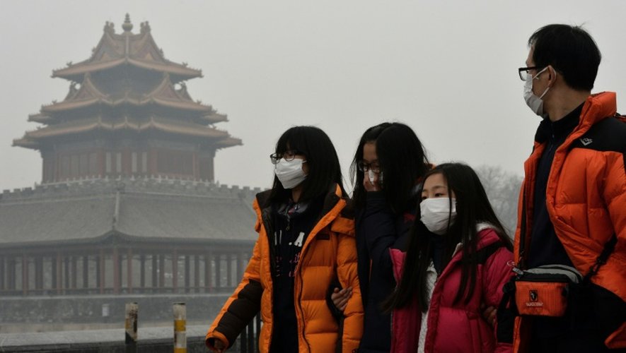 Des touristes chinois portent un masque alors qu'ils marchent près de la Cité intredite à Pékin le 26 février 2014