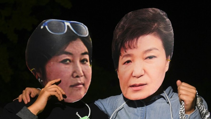 Des manifestants portant des masques de la présidente de Corée du sud Park Geun-Hye (d) et de son ex-confidente Choi Soon-Sil (g), dénoncent les liens entre elles lors d'un rassemblement à Séoul, le 27 octobre 2016