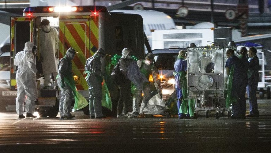 Une infirmière contaminée par le virus Ebola (c) en Sierra Leone descend d'une ambulance pour être placée dans un dispositif d'isolement sur le tarmac de l'aéroport de Glasgow avant d'être transportée par avion vers l'hôpital Royal Free de Londres, le 30 décembre 2014
