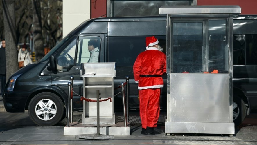 Un agent de sécurité en costume de père Noël à l'entrée d'un parking le 24 décembre 2014 à Pékin